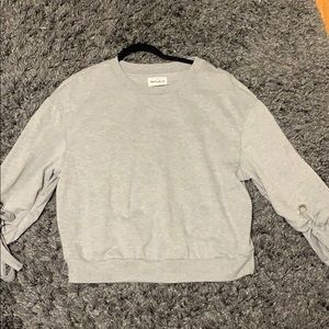 grey sweater with ties on the sleeve